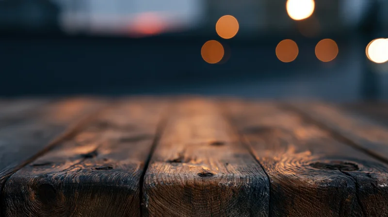 Low-angle view of rustic wooden tabletop with blurred lights in the background