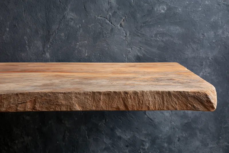 Weathered wooden shelf mounted against a dark textured wall with copyspace below