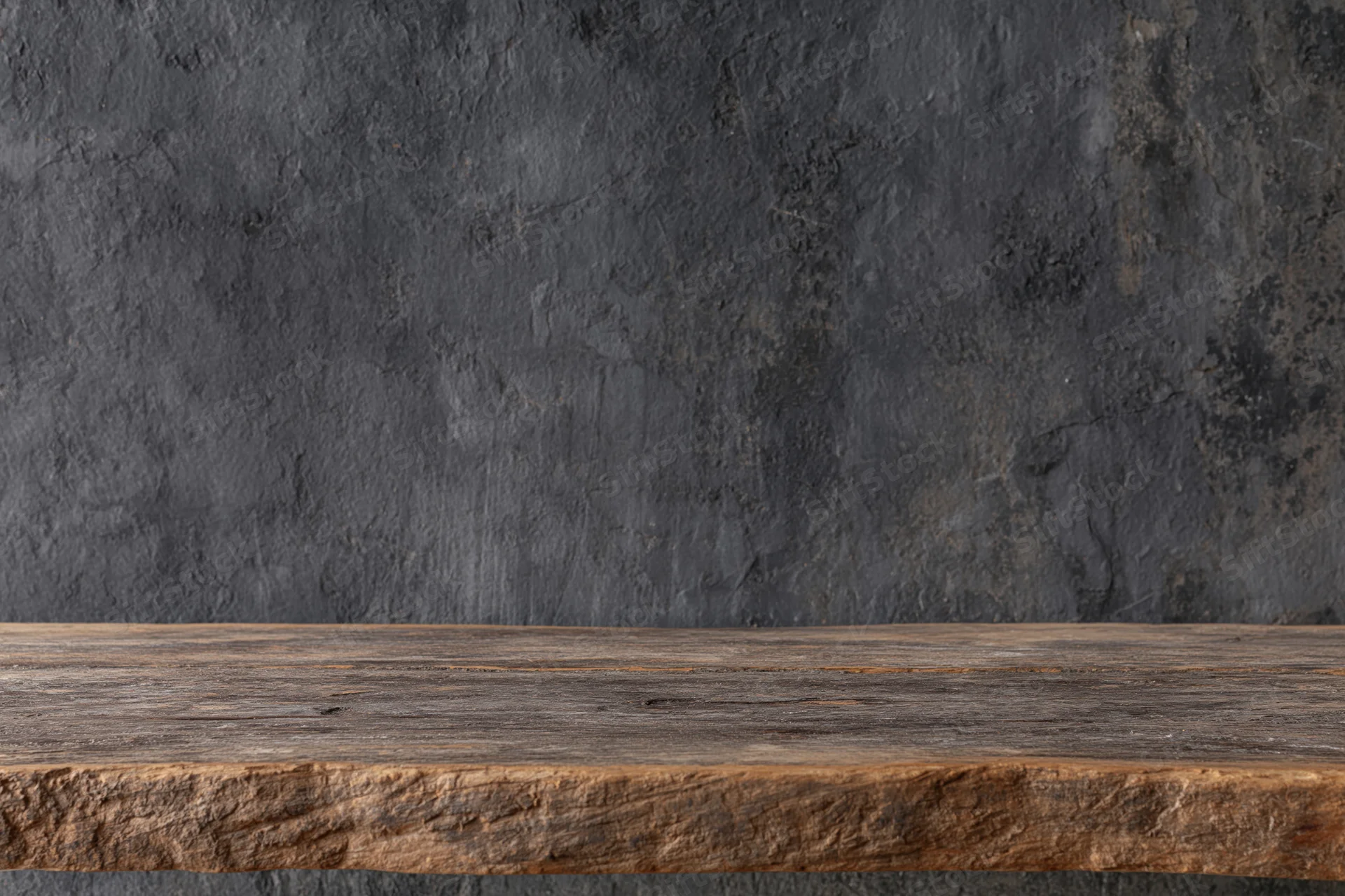 Weathered wooden shelf against dark textured concrete wall with copyspace