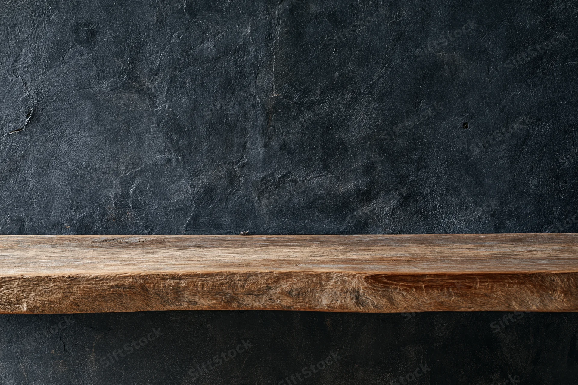 Weathered wooden shelf mounted against a dark textured wall in an interior space