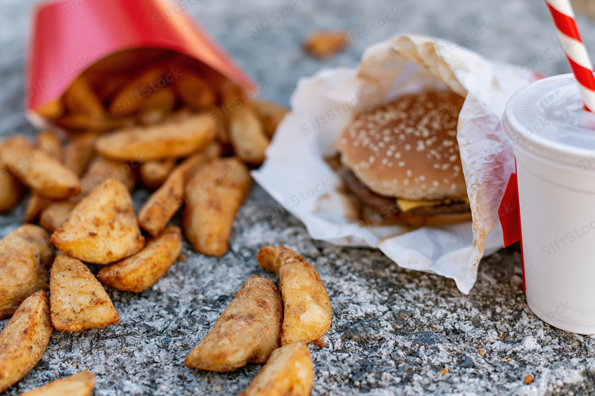 Fast food meal scattered on rough concrete ground