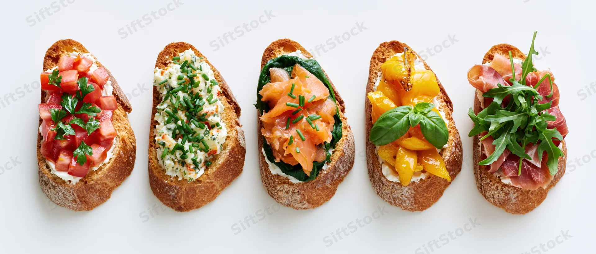 Five assorted bruschetta toasts arranged in a row on a white background