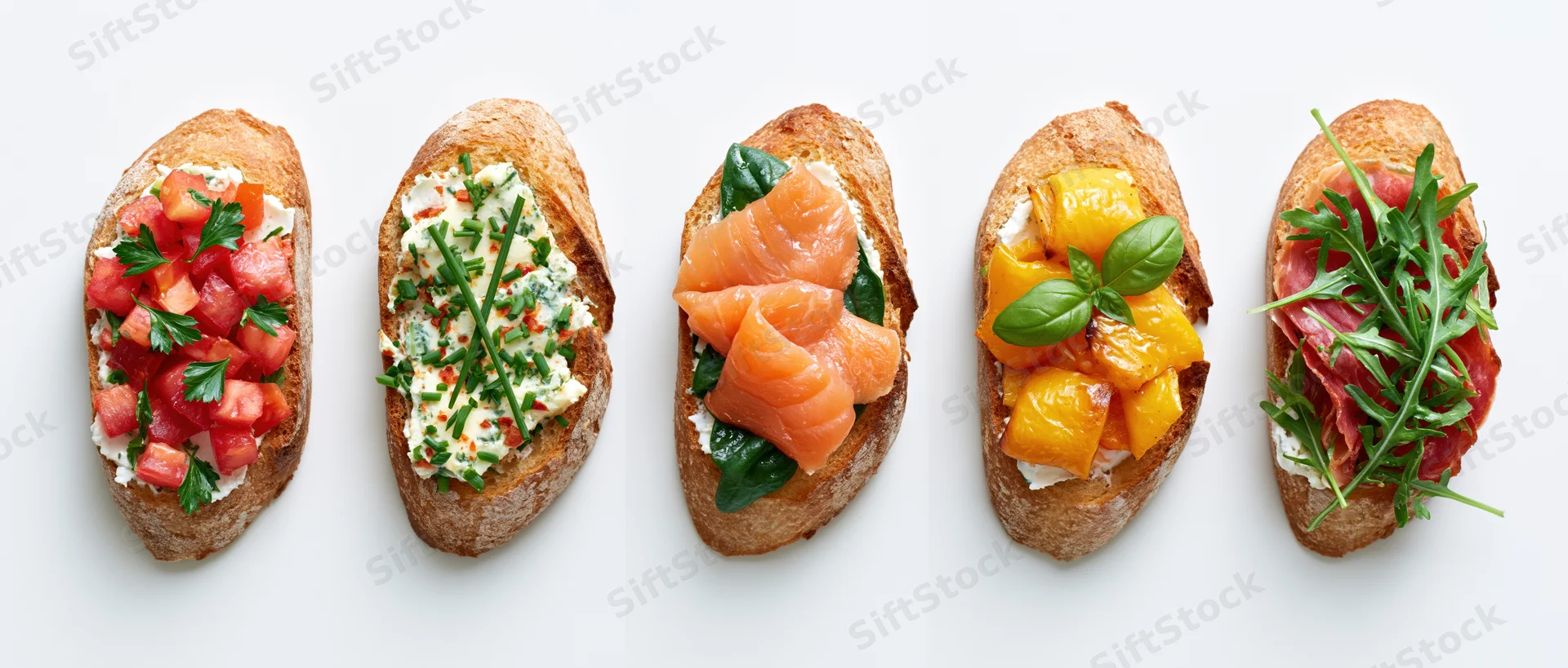 Five assorted bruschetta toasts arranged in a row on a white surface