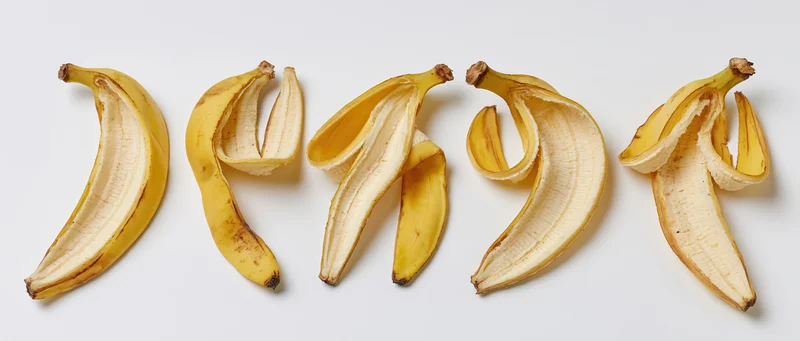 Five banana peels arranged in a horizontal row on a white background