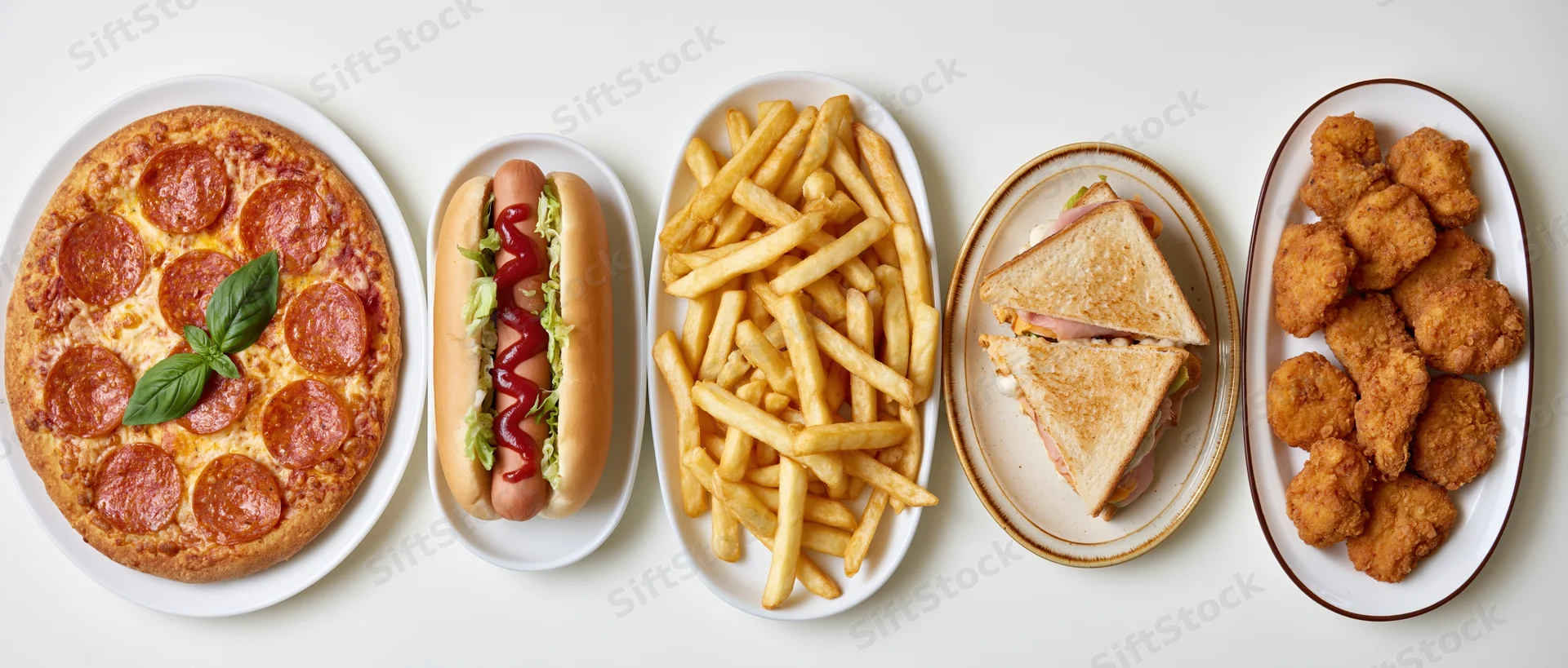 Five plates of fast food arranged in a horizontal row on a white surface