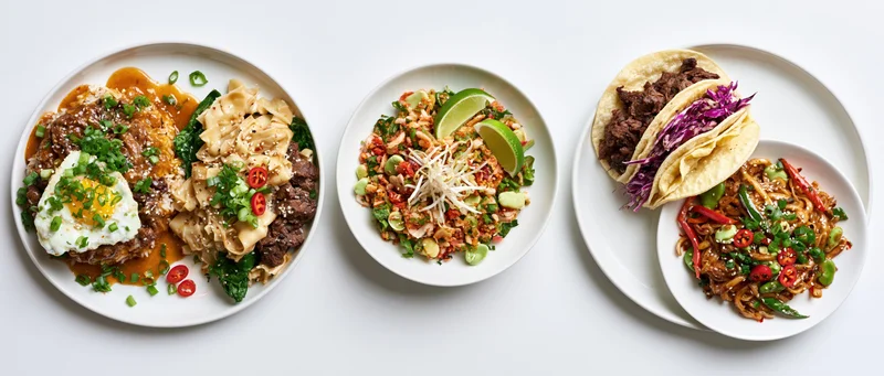 Five white plates with asian-inspired dishes arranged in a row on a white surface