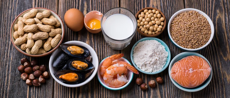 Common food allergens arranged in bowls on dark wooden surface