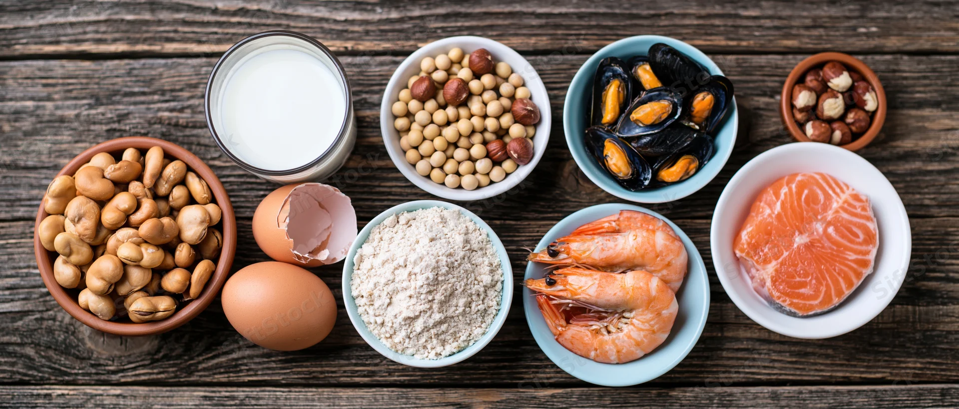 Various common food allergens arranged in bowls on a dark wooden table