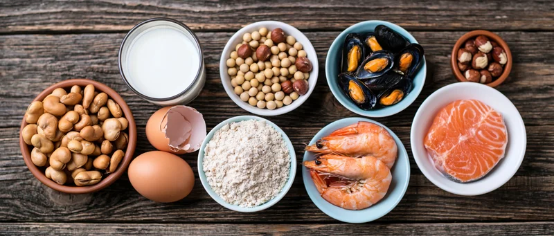Various common food allergens arranged in bowls on a dark wooden table