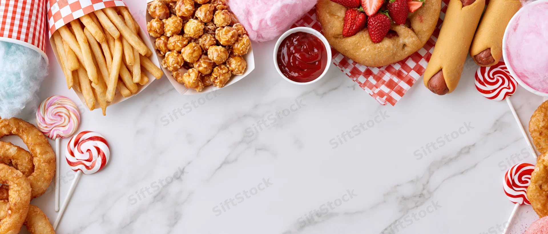 Carnival fair foods arranged in a border on a marble surface with copyspace in the center