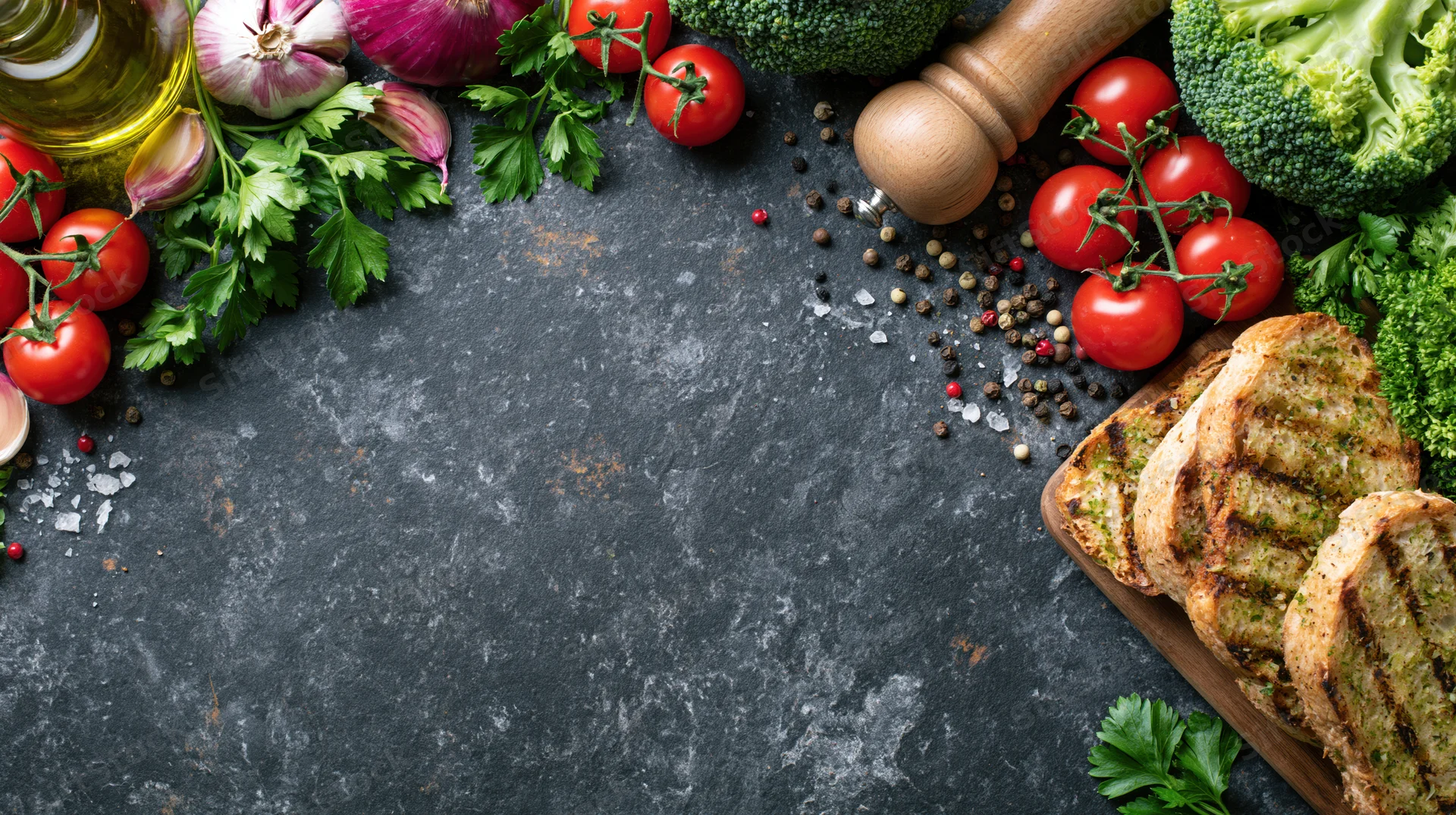 Fresh cooking ingredients arranged around dark countertop with copyspace