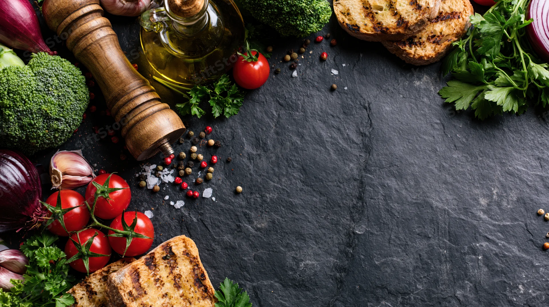 Fresh cooking ingredients arranged on dark slate surface with copyspace