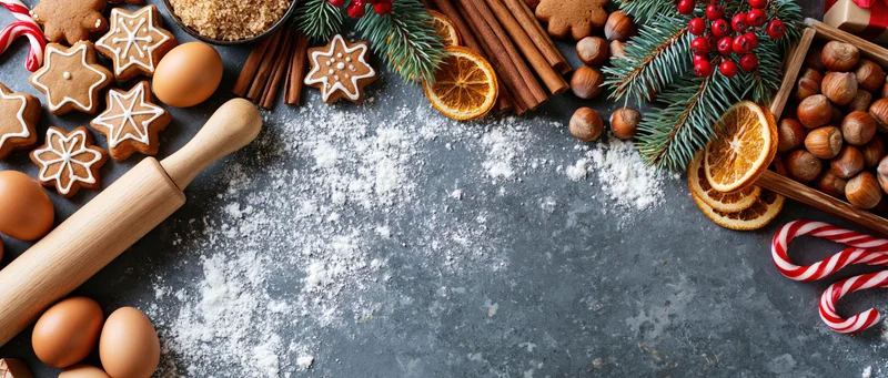 Christmas baking ingredients and tools arranged on a dark countertop with copyspace