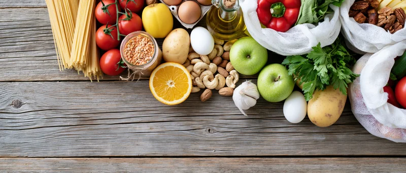 Assorted fresh grocery ingredients arranged on a rustic wooden table with copyspace below