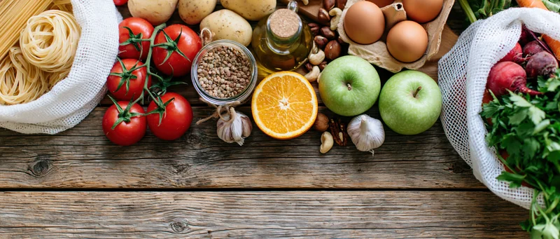 Assorted fresh groceries arranged on a rustic wooden surface with copyspace at bottom