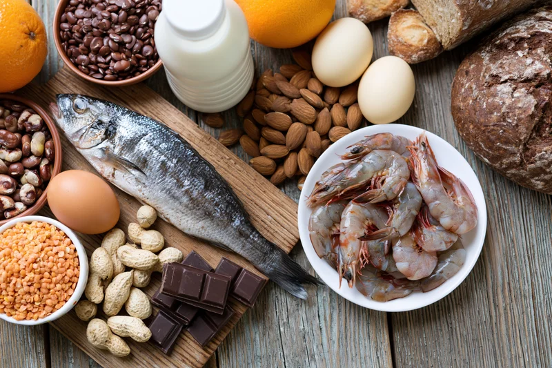 Various common food allergens arranged on a weathered wooden surface in a flat lay composition