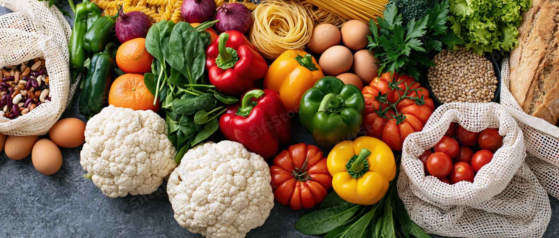 Fresh groceries arranged in a flat lay on dark grey concrete surface