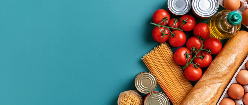Grocery staples arranged along the right edge of a blue surface with copyspace on the left