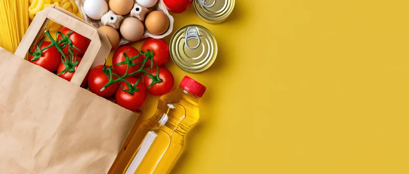 Grocery staples arranged on yellow surface with copyspace