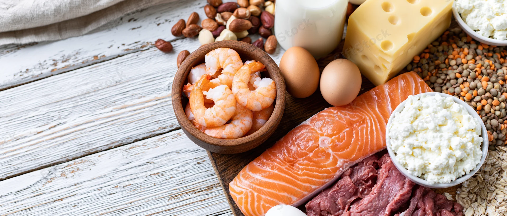 High-protein foods arranged on a white-painted wooden table in a flat lay composition