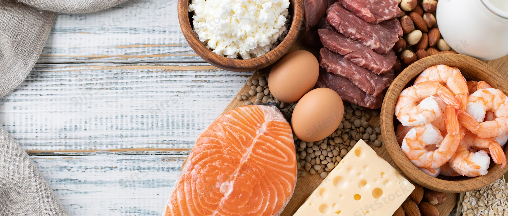 High-protein foods arranged on a white-painted wooden surface in a flat lay composition