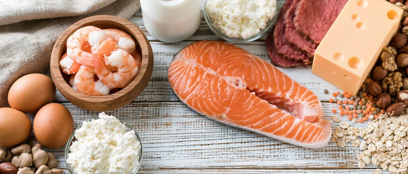 High-protein foods arranged on a white-painted wooden table in a flat lay composition