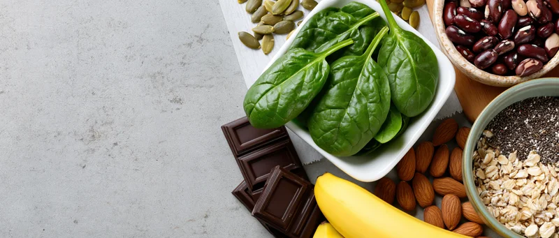 Magnesium-rich foods arranged in bowls and piles on a countertop with copyspace on the left