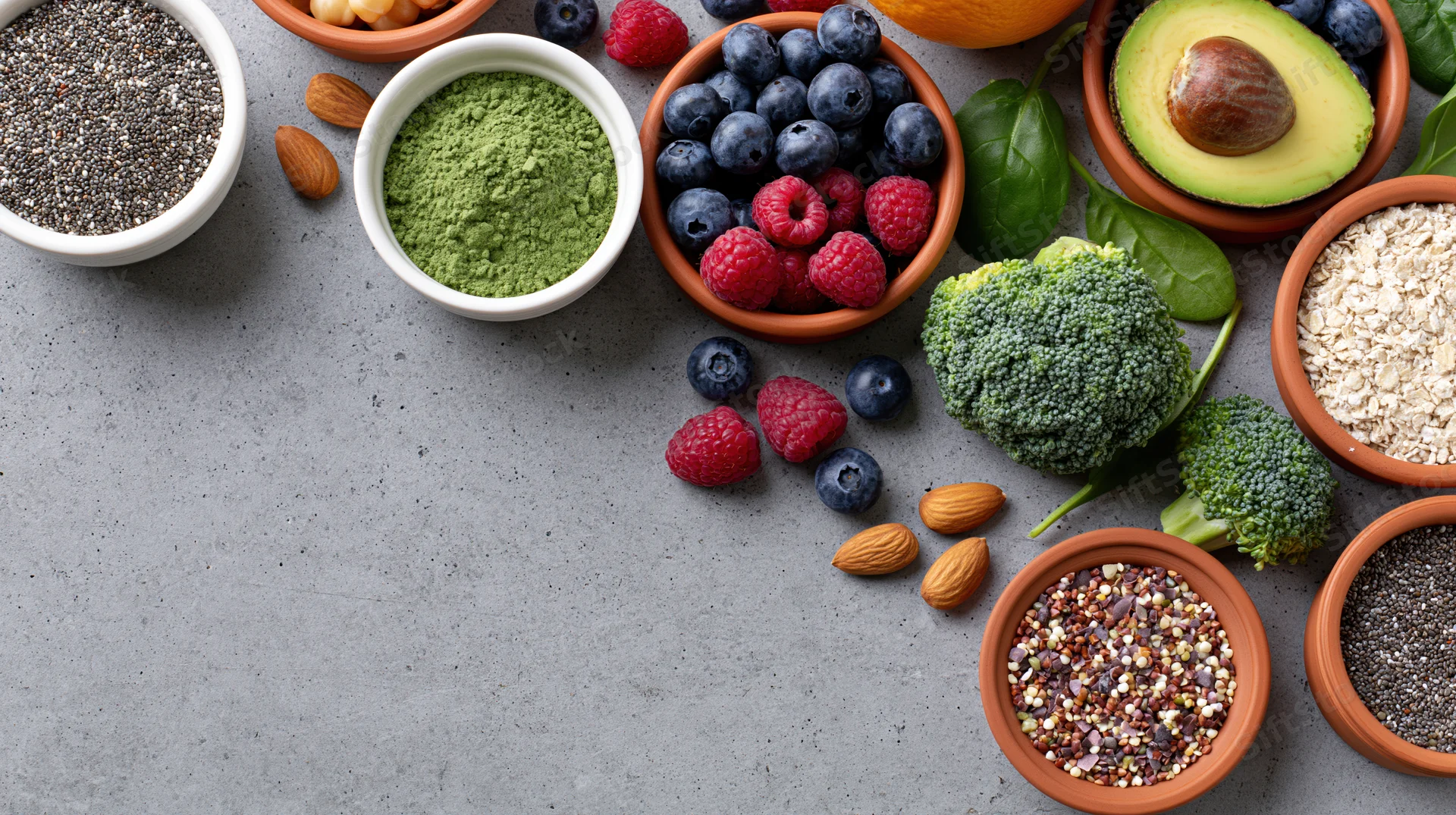 Superfoods and healthy ingredients arranged in bowls on a gray surface with copyspace