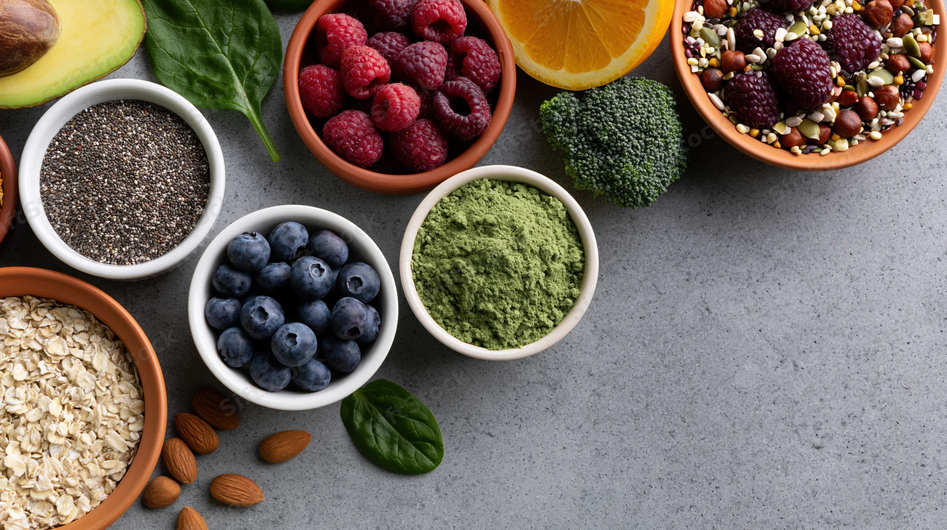 Superfoods and healthy ingredients arranged in bowls on a gray surface with copyspace