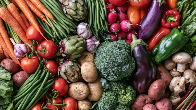Overhead flat lay of fresh raw vegetables arranged densely in a kitchen setting