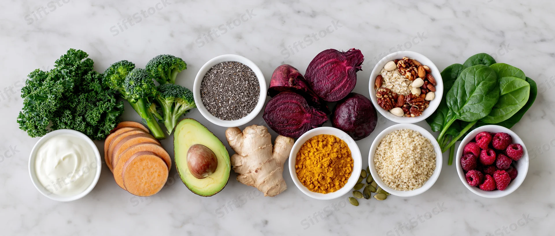 Assorted healthy whole foods arranged in bowls and piles on a marble countertop