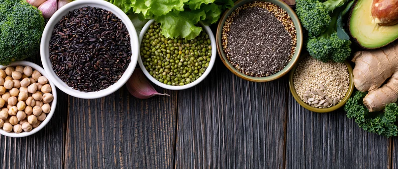 Assorted superfoods and legumes arranged on a dark wooden table with copyspace