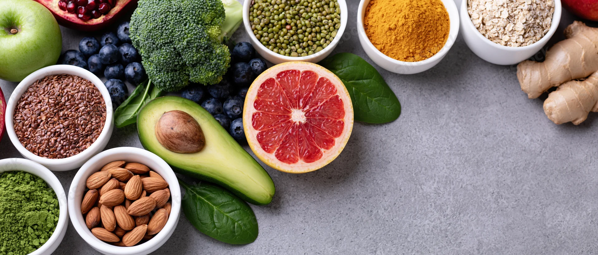 Assorted whole foods arranged in a flat lay overhead composition on a gray surface with copyspace