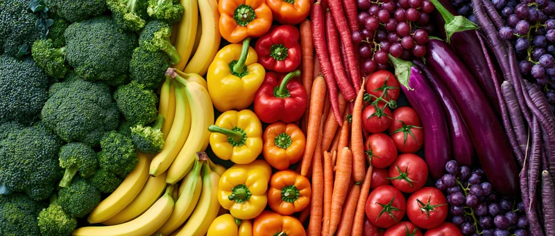 Overhead flat lay of fresh fruits and vegetables arranged in colorful rows