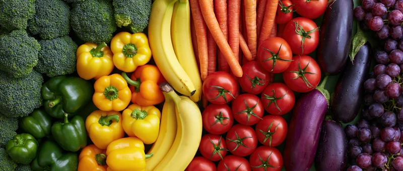 Overhead flat lay of fresh fruits and vegetables arranged in colorful rows