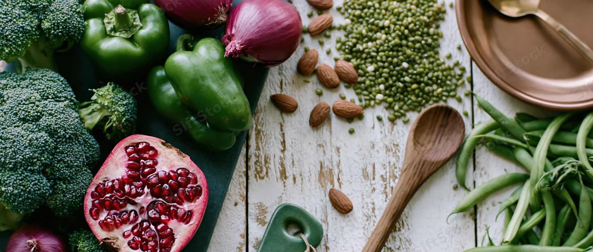 Fresh vegetables and fruits arranged with nuts and legumes on a wooden table in a flat lay overhead composition