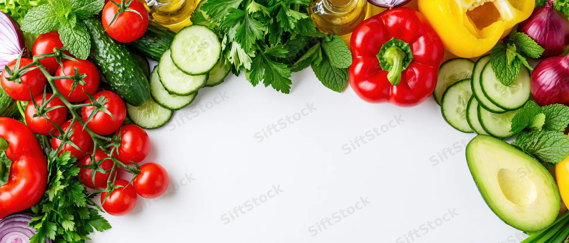 Fresh salad ingredients arranged as a border frame along the top and sides of a white surface with copyspace in the center