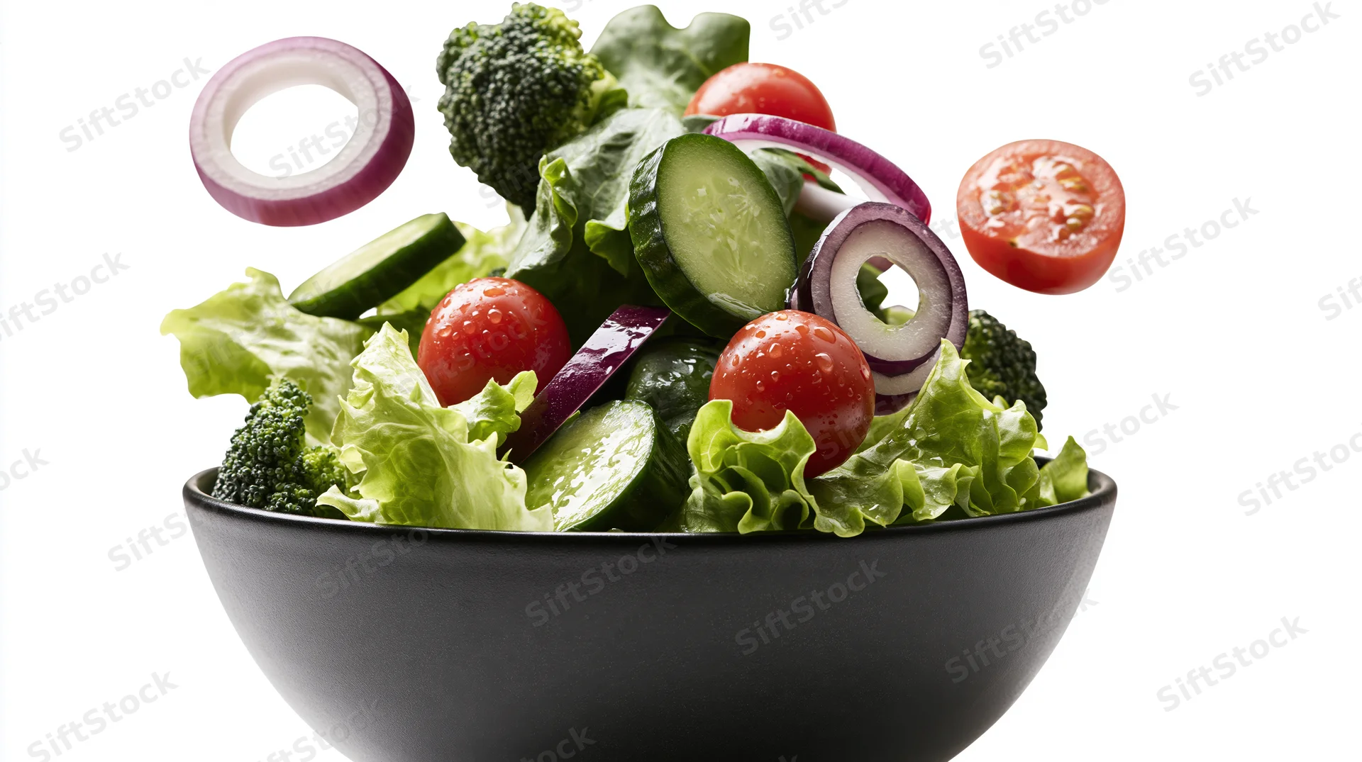 Fresh salad ingredients floating above a dark ceramic bowl
