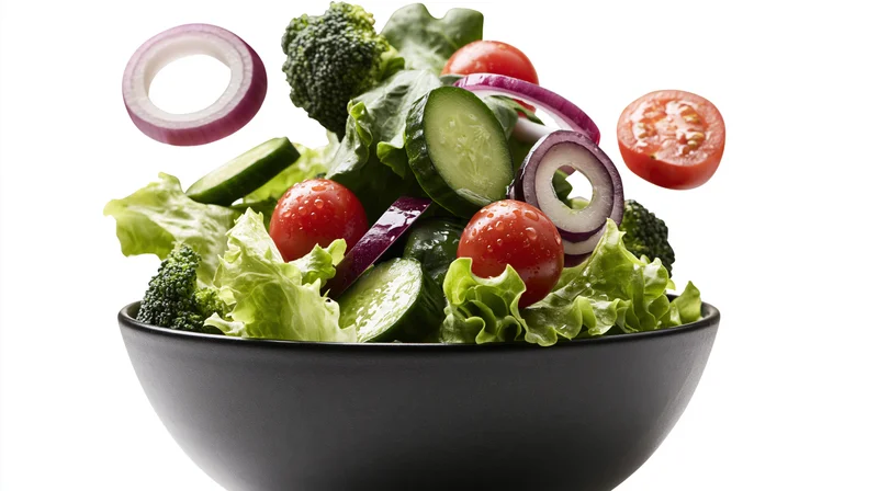 Fresh salad ingredients floating above a dark ceramic bowl