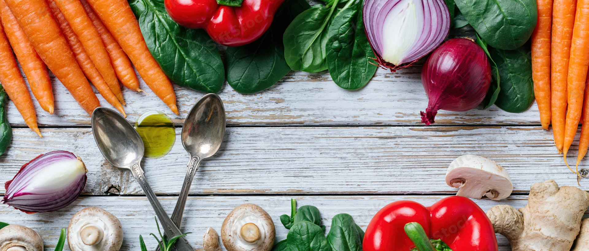 Fresh vegetables and cooking utensils arranged in a flat lay on a white wooden table
