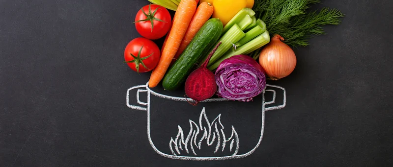 Fresh vegetables arranged in a chalk-drawn pot on a blackboard surface