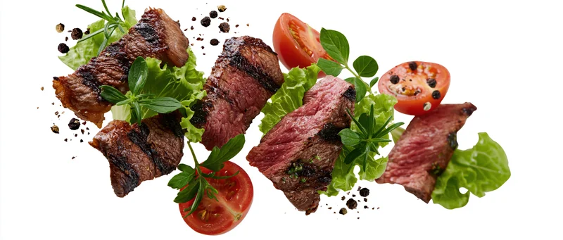 Grilled beef steak slices and fresh vegetables suspended midair on white background