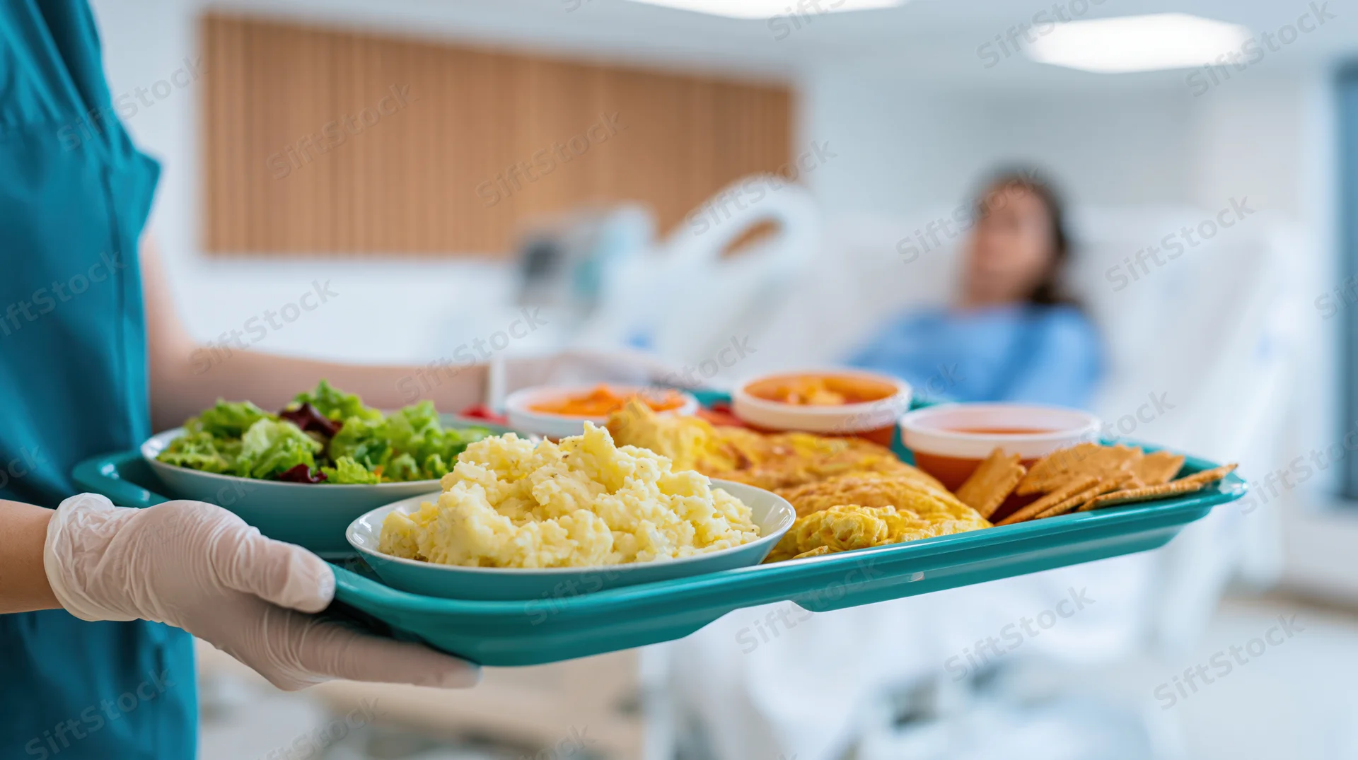 Nurse holding a tray of hospital food in a patient's room