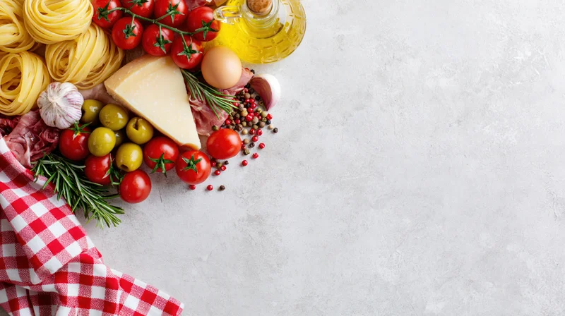 Italian cooking ingredients arranged along the top-left border of a countertop with copyspace