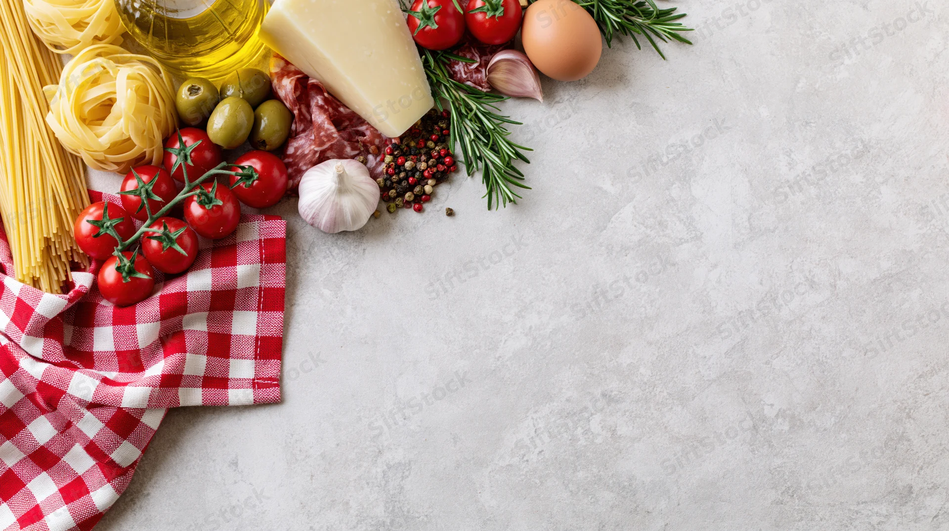 Italian cooking ingredients arranged along the top-left border on a white countertop with copyspace