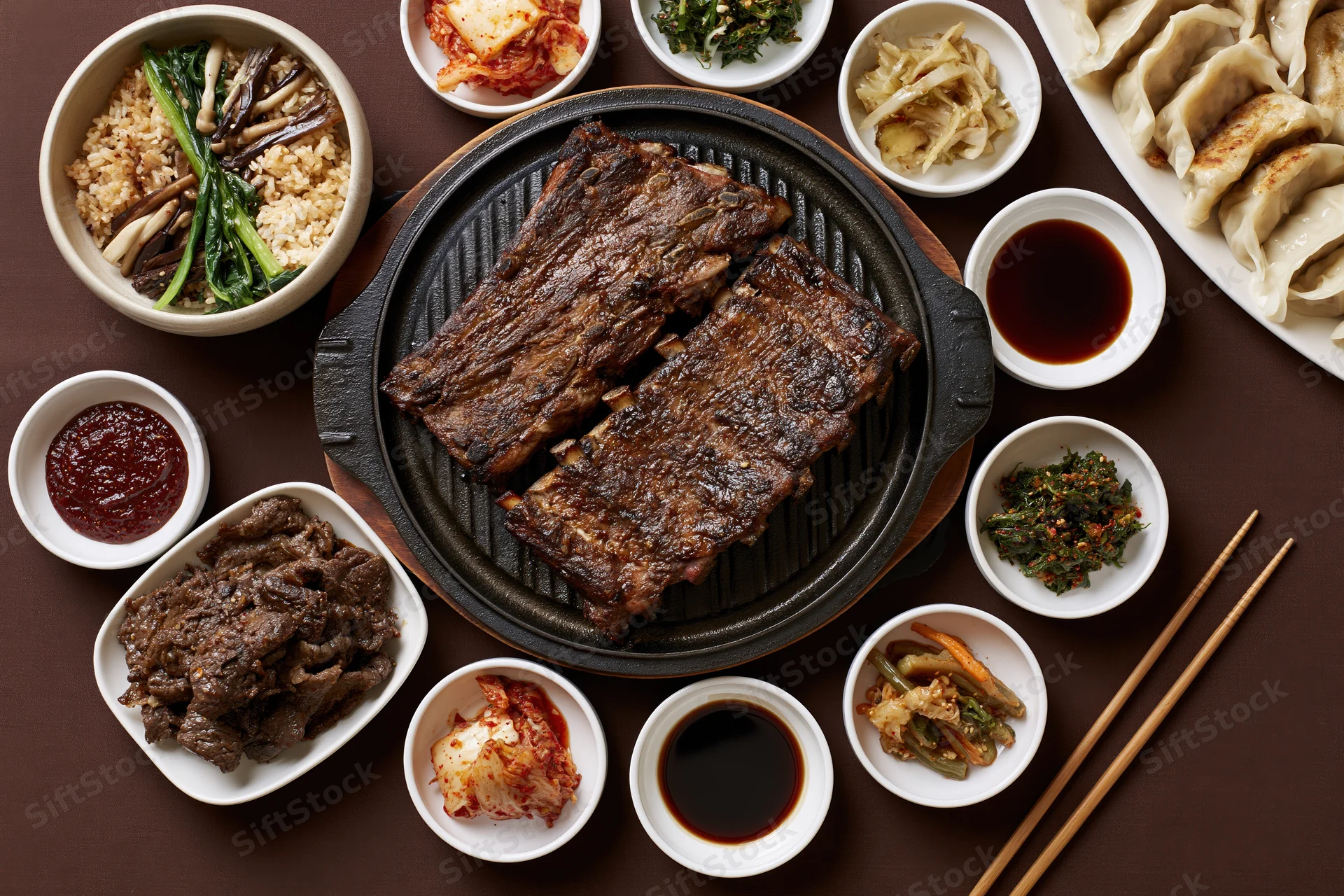 Overhead view of korean barbecue spread with grilled galbi ribs and side dishes on table