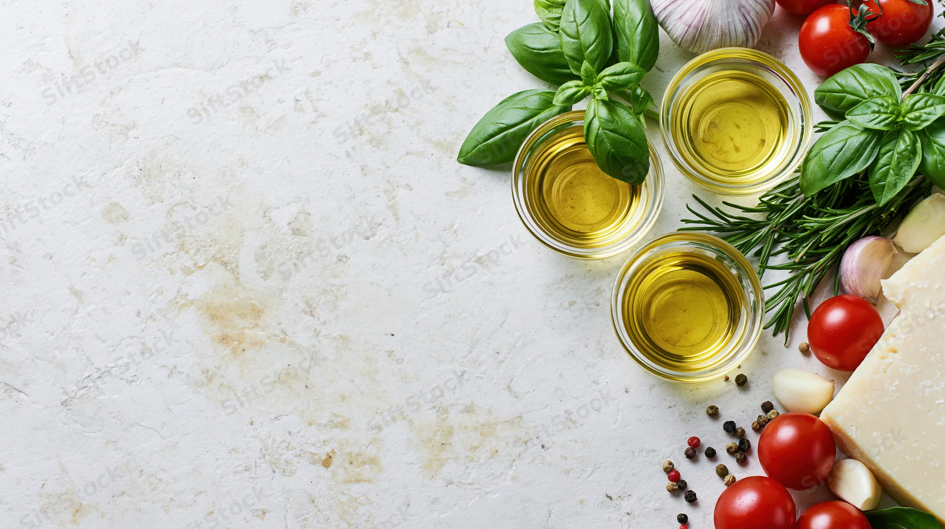 Mediterranean cooking ingredients arranged along the right edge of a white marble countertop