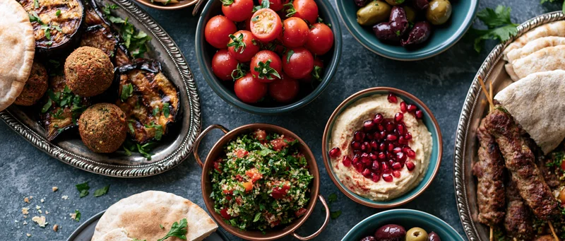Middle eastern mezze spread with hummus, falafel, tabbouleh and pita on dark slate table