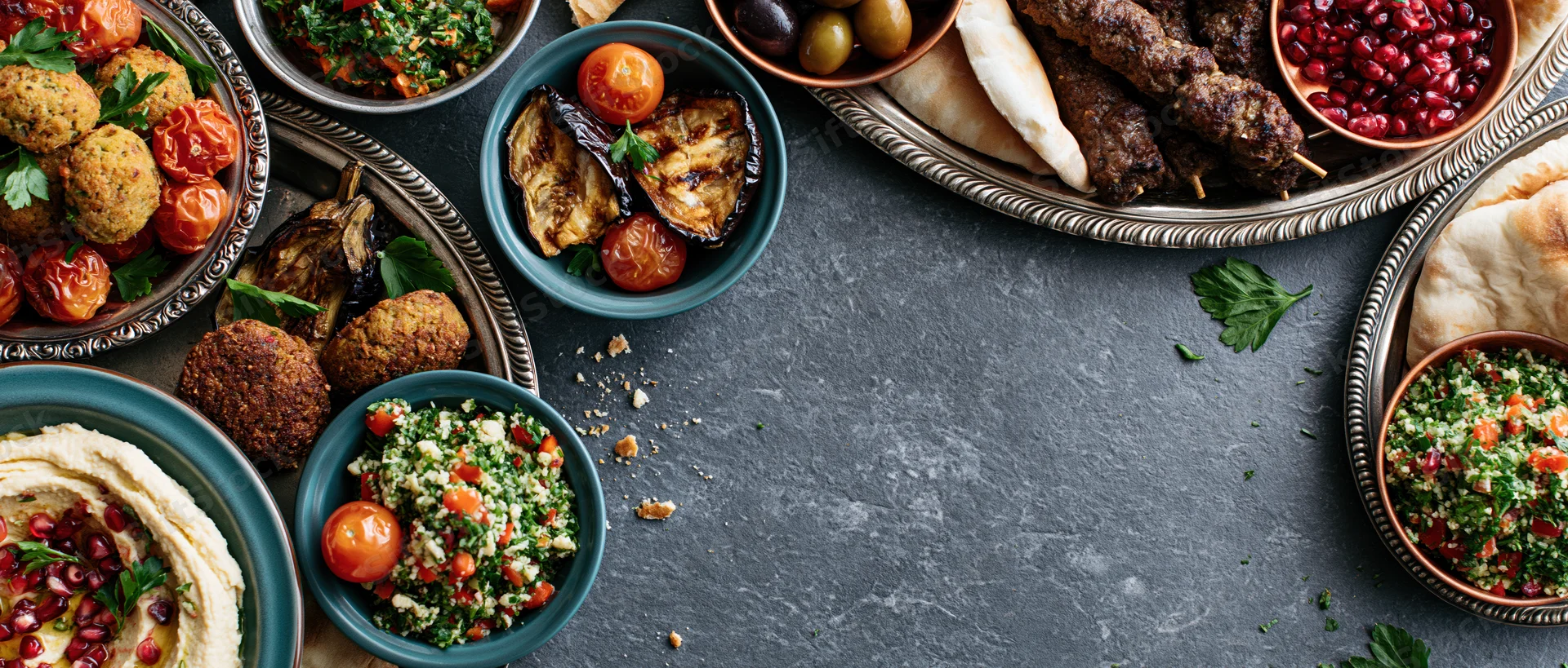 Middle eastern mezze spread arranged on dark slate table with various dishes and garnishes