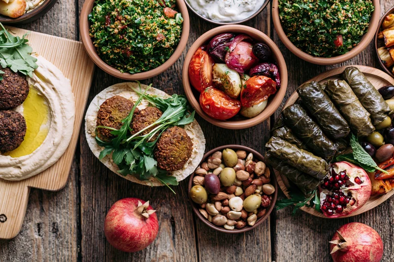 Middle eastern mezze spread with hummus, falafel, tabbouleh and stuffed grape leaves on a rustic wooden table